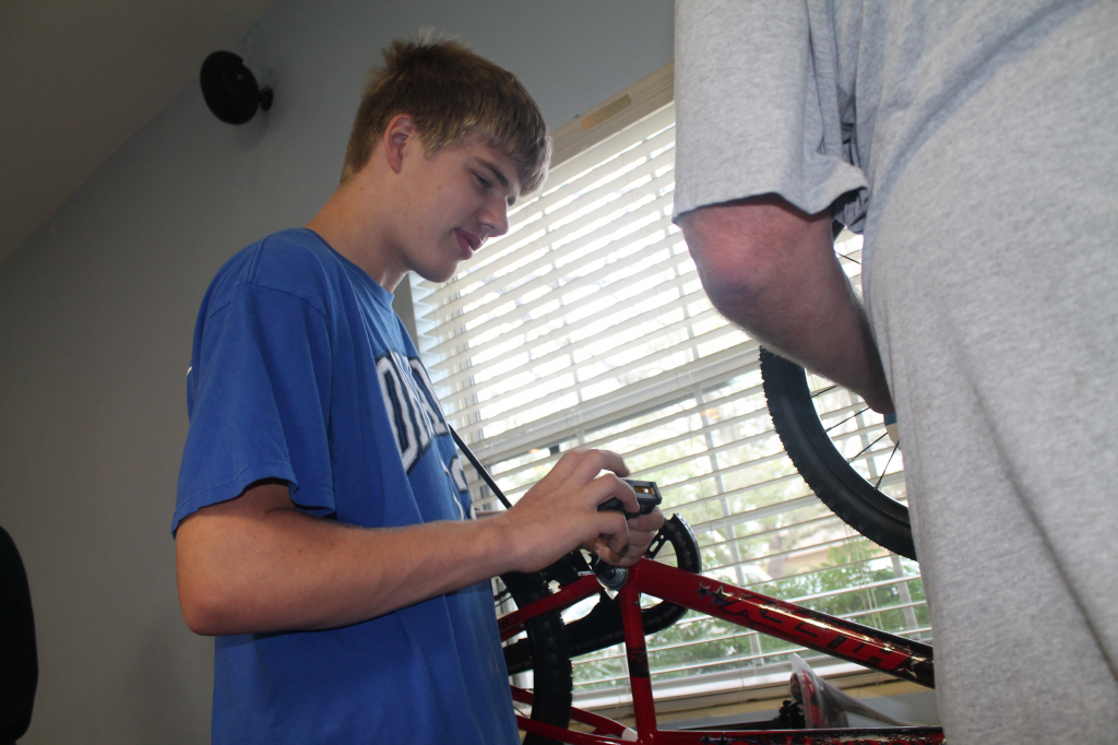 GEAR UP.  Key Club member Chris Ellis helps Kiwanis Club member build bikes for kids in need.