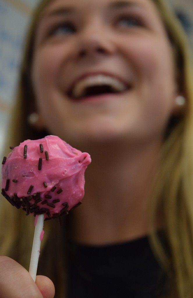 YUMMY. Club member Kaylin Garrett, junior, enjoys a chocolate cake pop covered in pink frosting. 
