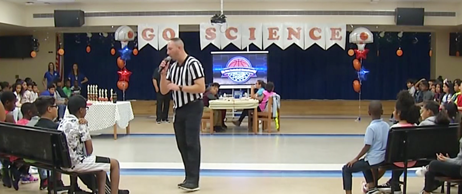Dressed as a referee, Justin MacDonald explains the sports theme Science Competition to student observers.